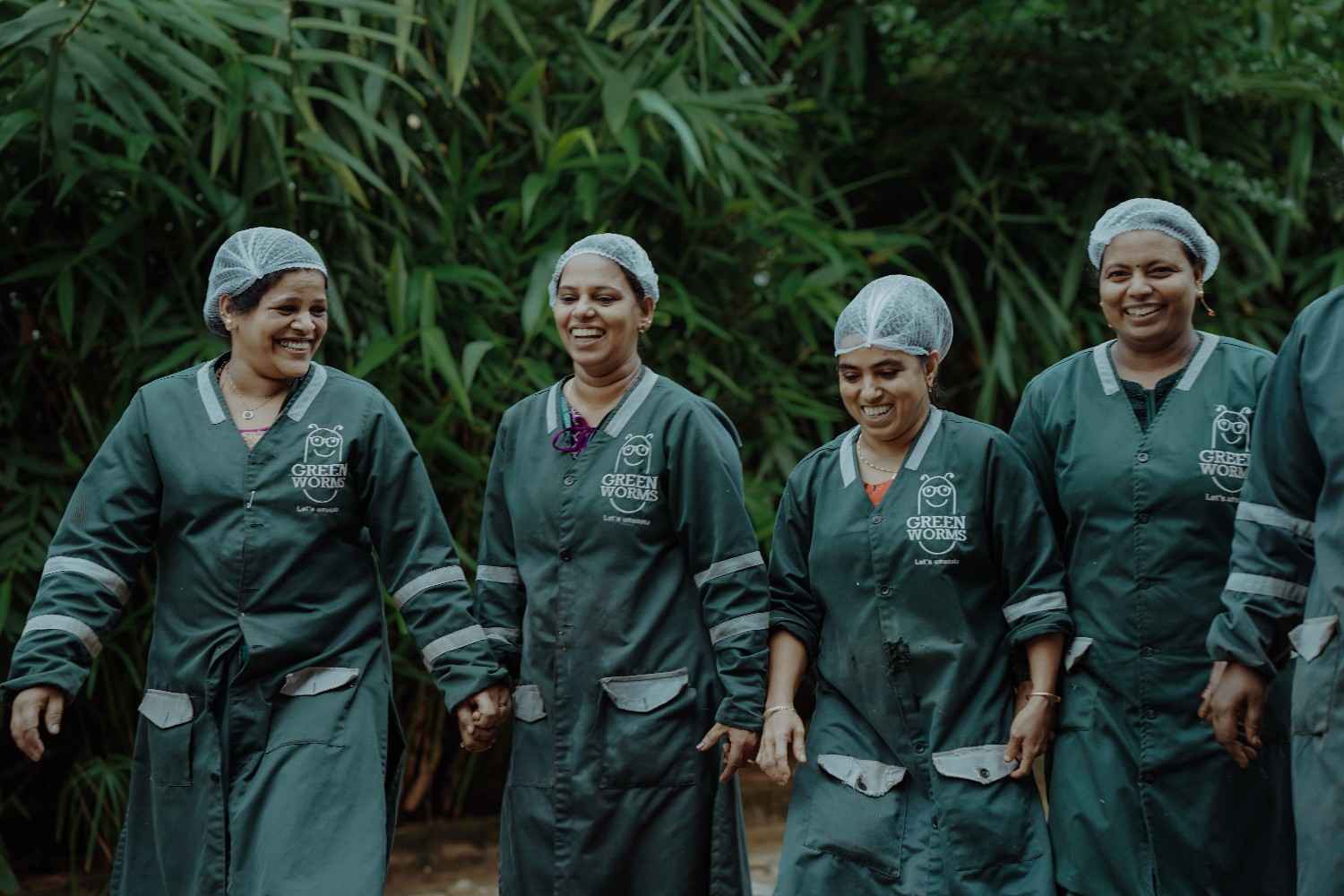 Textile recovery facility with workers in green uniforms sorting and organizing textile materials under warehouse structure